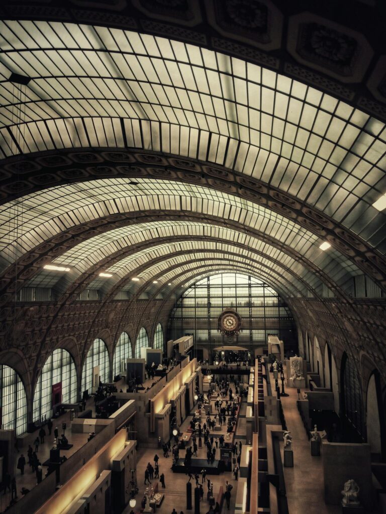 From above of people inside spacious Orsay Museum with exhibits of paintings and sculptures
