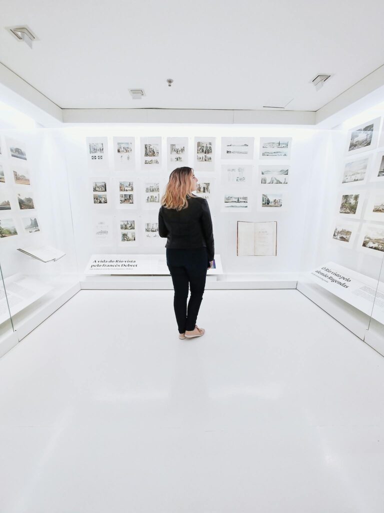 Woman standing in modern museum with pictures on walls